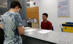 Un treballador de Correus explica el procediment per demanar el vot postal a un ciutadà